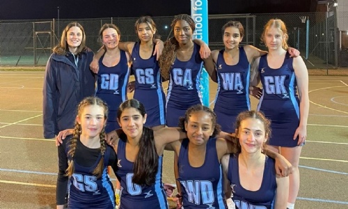 U14 netball girl team posing as a team, along with PE teacher